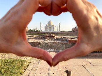 Cropped image of hands against building in city