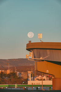 Low angle view of building against clear sky and full moon