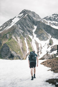 Rear view of man walking on snowcapped mountain