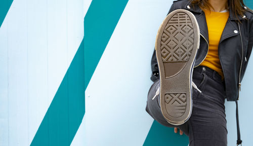 Woman showing the sole of her sneaker on a blue background.