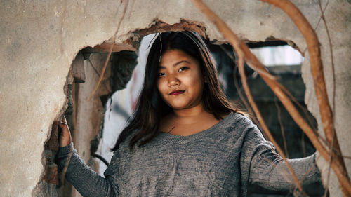 Portrait of young woman standing against wall