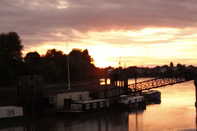Silhouette boats in lake against dramatic sky during sunset