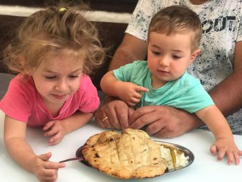 High angle view of siblings eating food on table