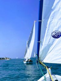 Sailboat sailing in sea against clear blue sky