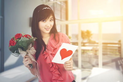 Portrait of a smiling young woman holding red rose