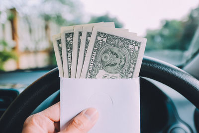 Close-up of cropped hand with paper currency in car