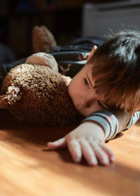 Pensive baby boy hugging a toy bear in the kids room at nap time
