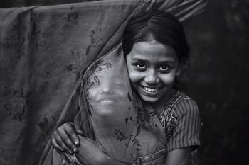 Portrait of smiling girl with friend by curtain