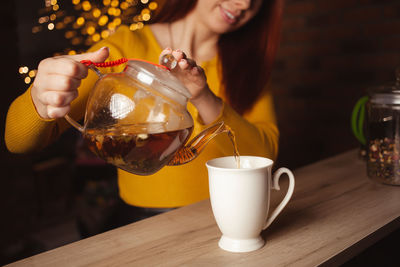 Woman brews tea, delicious aroma, appetizing. white porcelain cup, drink, tea shop. cozy atmosphere