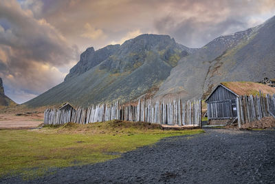 Viking houses surrounded by wooden fence under vestrahorn mountain at sunset
