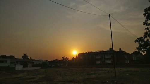 Houses on field against sky during sunset