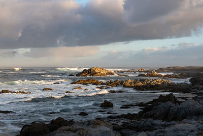 Morning clouds rainbow over rocky shore  along the pacific ocean coast on monterey bay california