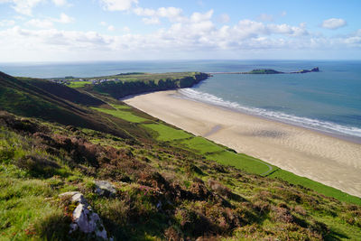 Gower peninsular rhossilli bay panoramic with green hills surrounding the sandy bay - green welsh