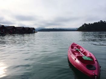 Boats in river against cloudy sky