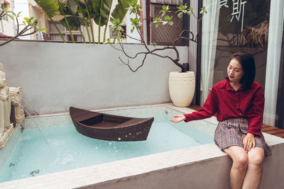 Portrait of a smiling young woman sitting on potted plant