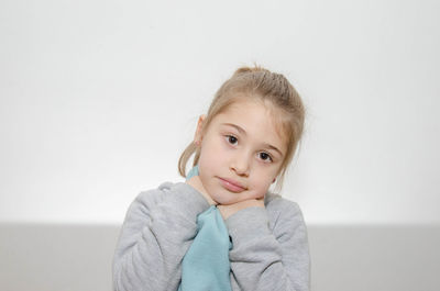 Portrait of cute girl wearing blue scarf standing against wall