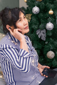 Full length of woman standing by christmas tree