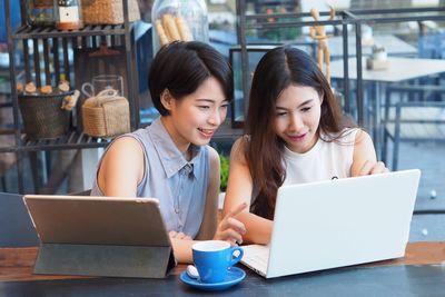 Young woman using mobile phone while sitting on table