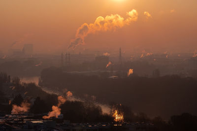 Smoke emitting from city against sky during sunset