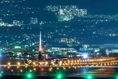 Airplane landing on illuminated airport at night