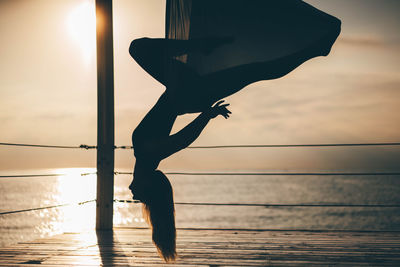 Low angle view of silhouette woman walking on beach during sunset