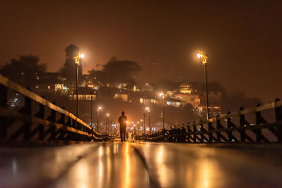 Illuminated bridge over river against sky in city at night