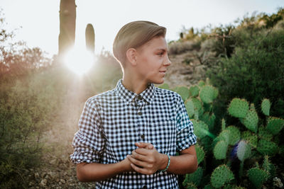 Smiling young man standing against plants