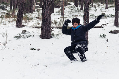 Full length of boy playing with snow in forest