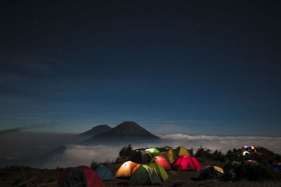 Illuminated tents on mountains against sky at night