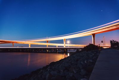 Bridge over river against clear blue sky at night