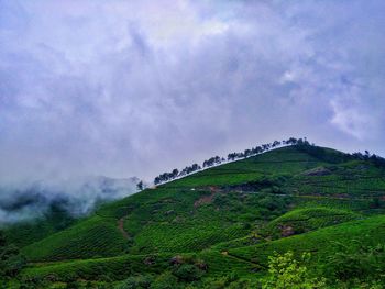 Scenic view of green mountains against cloudy sky