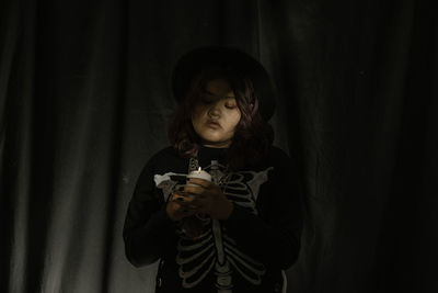 Young asian woman teen in costume witch and hold candle on black cloth background of halloween. 