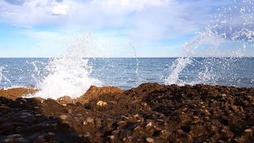 Waves splashing on shore against sky
