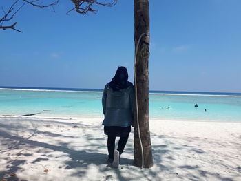 Rear view of woman at beach against sky