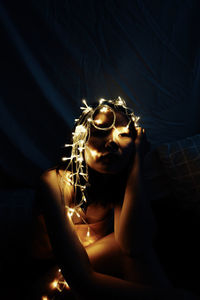 Portrait of woman holding illuminated lighting equipment