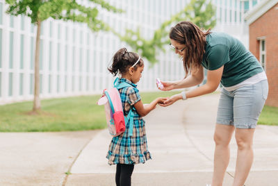 Young millennial mother sending daughter off back to school