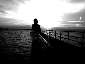 Silhouette man standing on sea against sky