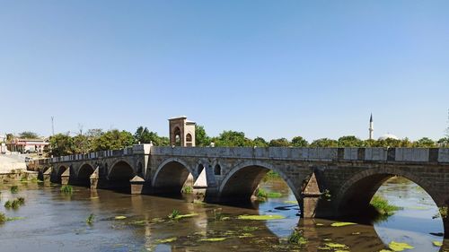 Arch bridge over river against clear sky