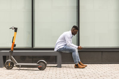 Young man using smart phone by wall