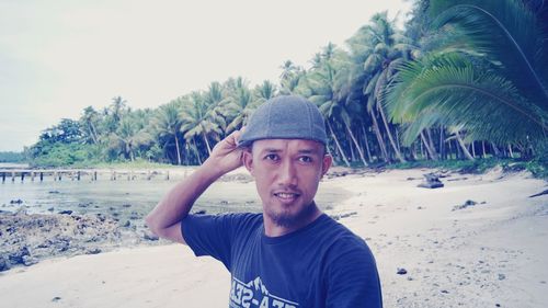 Portrait of smiling young man on beach against clear sky