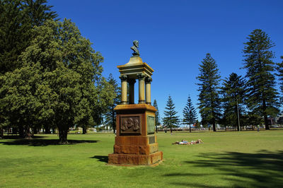 Gazebo by trees against clear blue sky