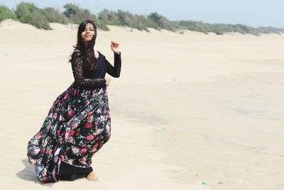 Portrait of young woman standing on sand at beach