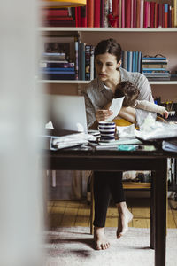 Businesswoman taking care of baby boy while working at home