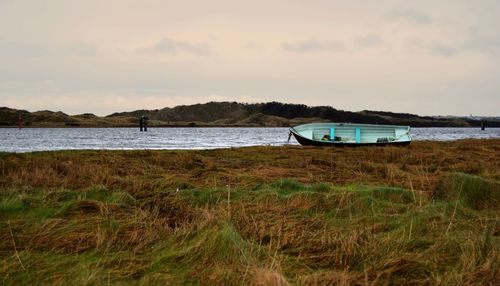 Boat at riverbank against sky