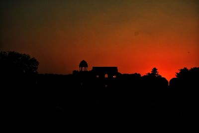 Silhouette of building against orange sky