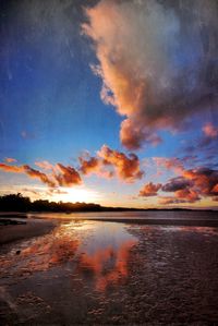 Scenic view of beach with clouds reflection at sunset