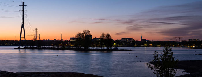 Panorama from the beach towards the city during a vivid sunset. silhouette of an electricity pylon