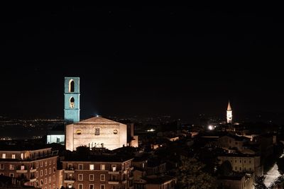 Illuminated buildings in city against clear sky at night