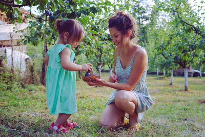 Girl and woman standing by plants against trees