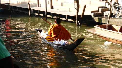 Rear view of monk on boat sailing in river